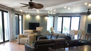 A spacious living area with a large sofa, a dining table with chairs, and a ceiling fan. - Stunning Ocean View 2BR/2BA Condo in Exclusive 1800 Atlantic Community (Key West)