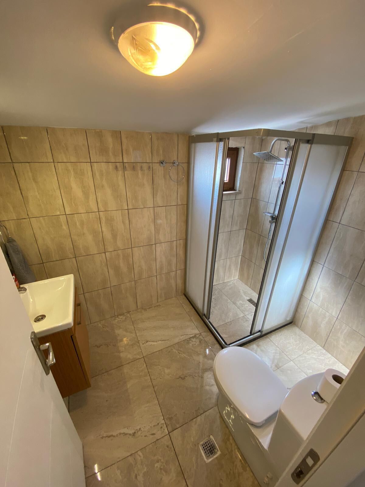 A bathroom with a shower, toilet, sink, and a mirror.