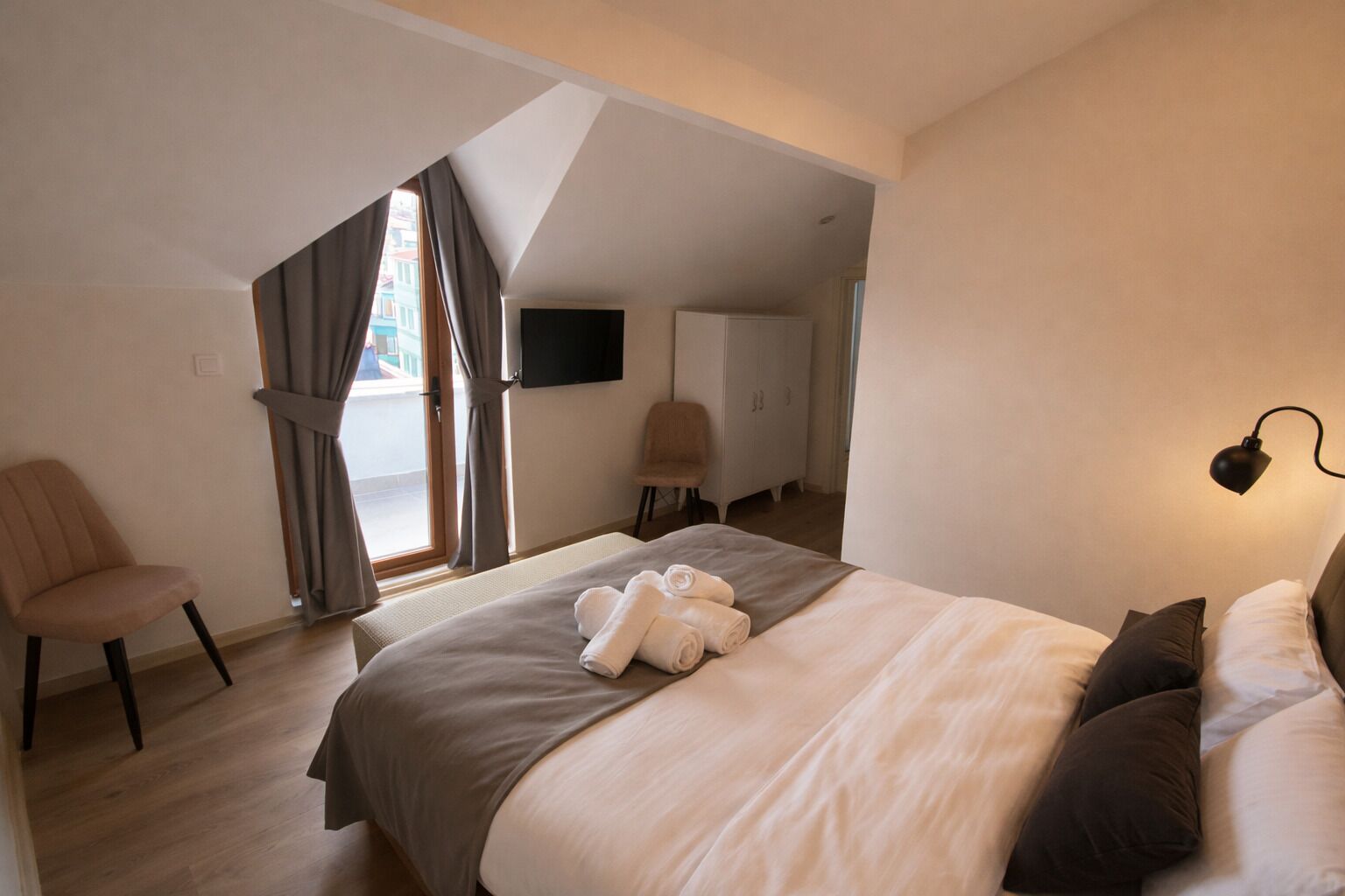 Un dormitorio con cama, una silla, un televisor y un escritorio.