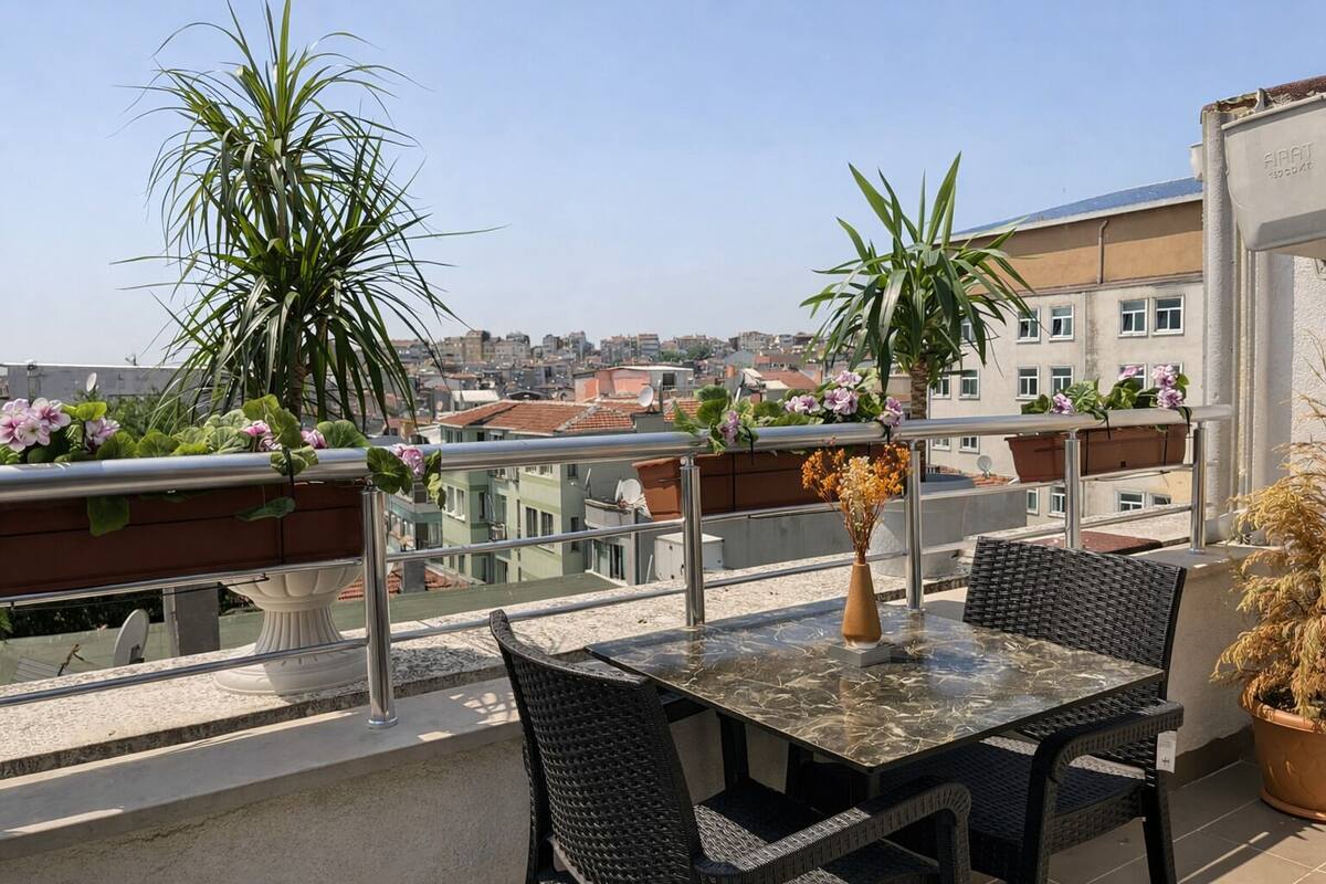 A balcony with a table, chairs, potted plants, and a city view.