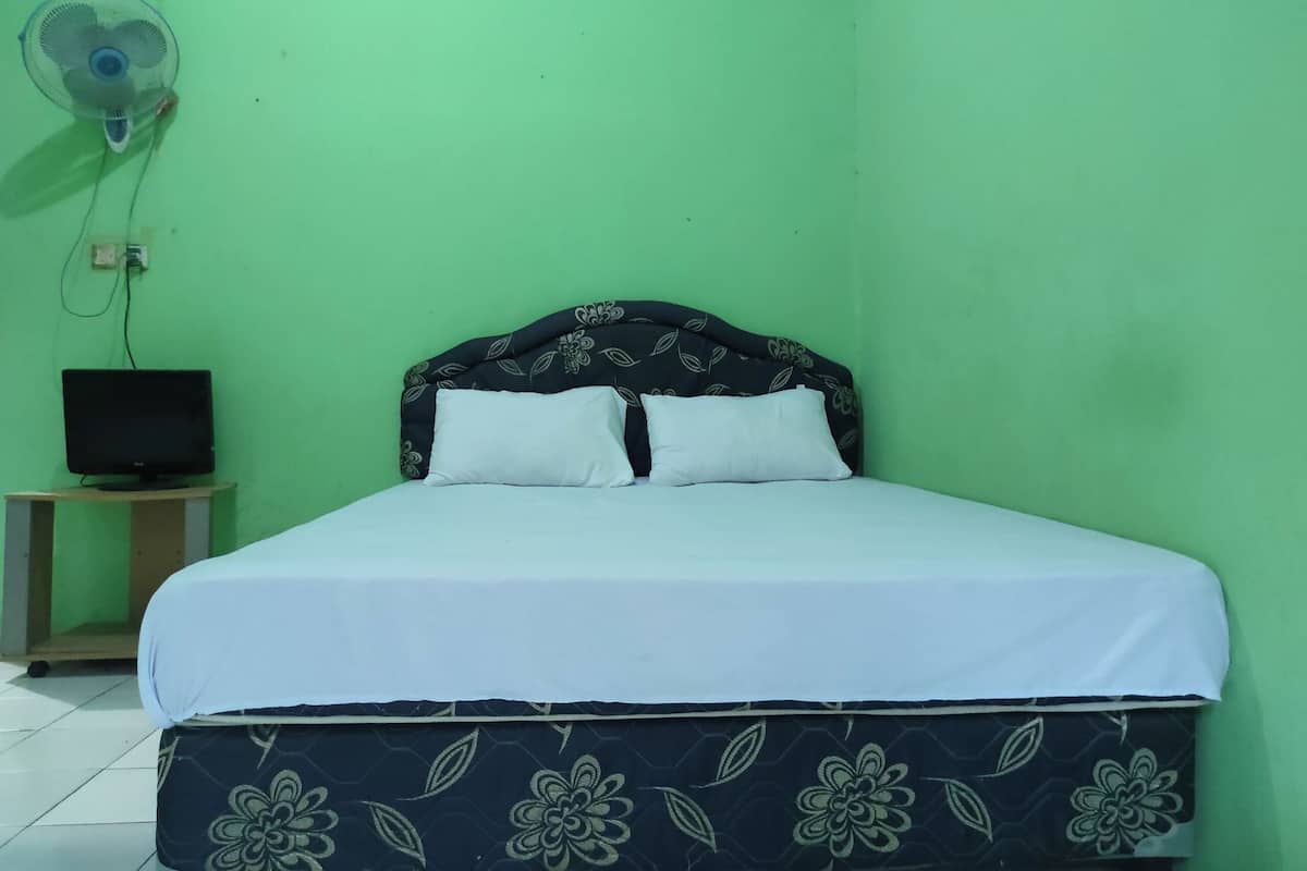 A room with a bed, a television on a stand, and a wall-mounted fan.