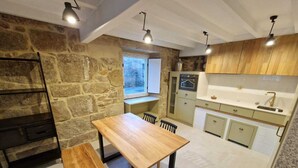 Une cuisine compacte avec un mur en pierre, des placards en bois, un four encastré et une fenêtre.