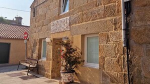 Un bâtiment en pierre avec un toit en tuiles, un banc et un pot de fleurs.