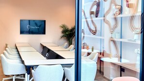 A modern meeting room with a 'Stay here' sign, a large table, and comfortable chairs.