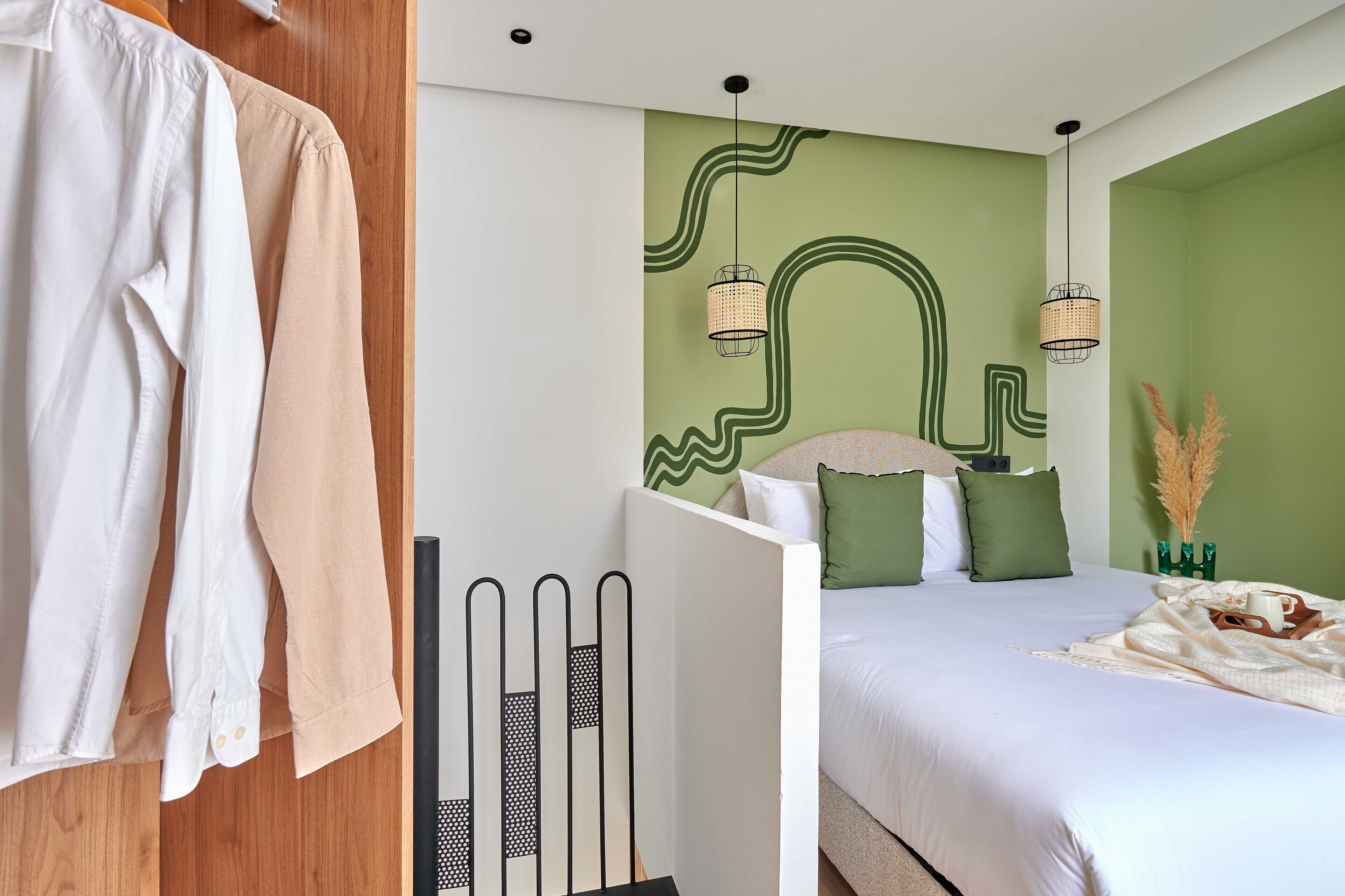 Een slaapkamer met een bed, een kledingkast en een muur met een abstract groen ontwerp.