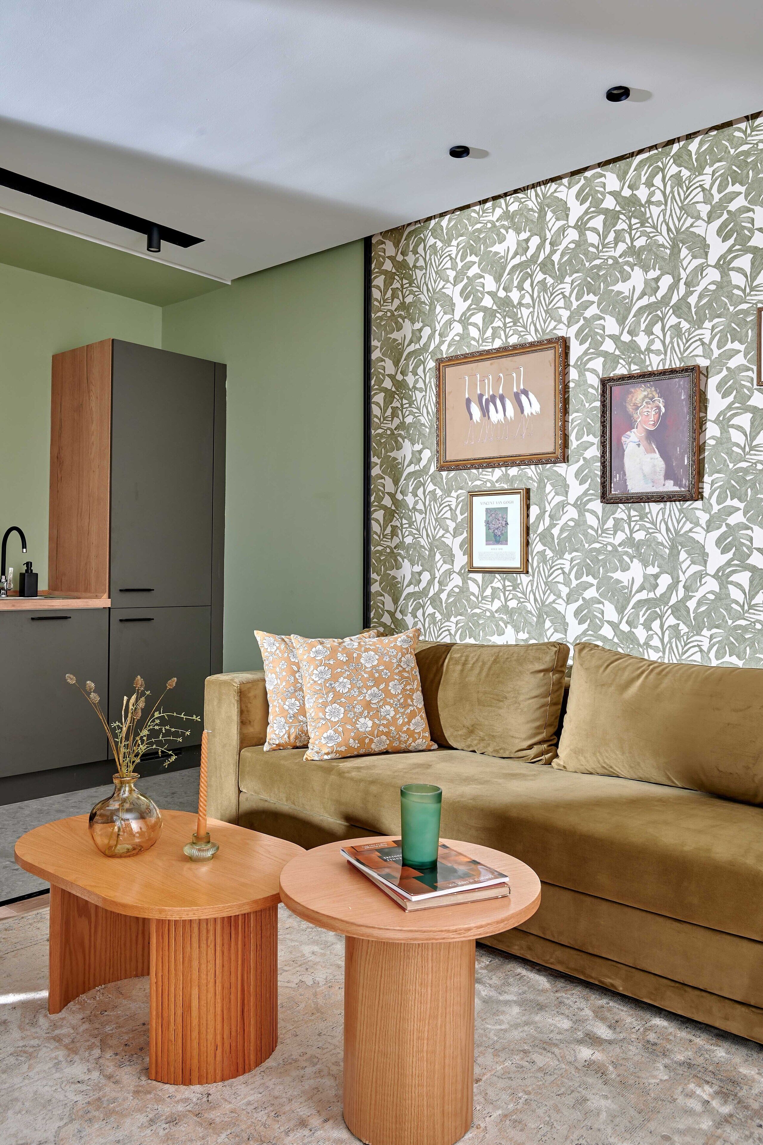 A modern living room with a sofa, two wooden side tables, a vase, and framed pictures on the wall.