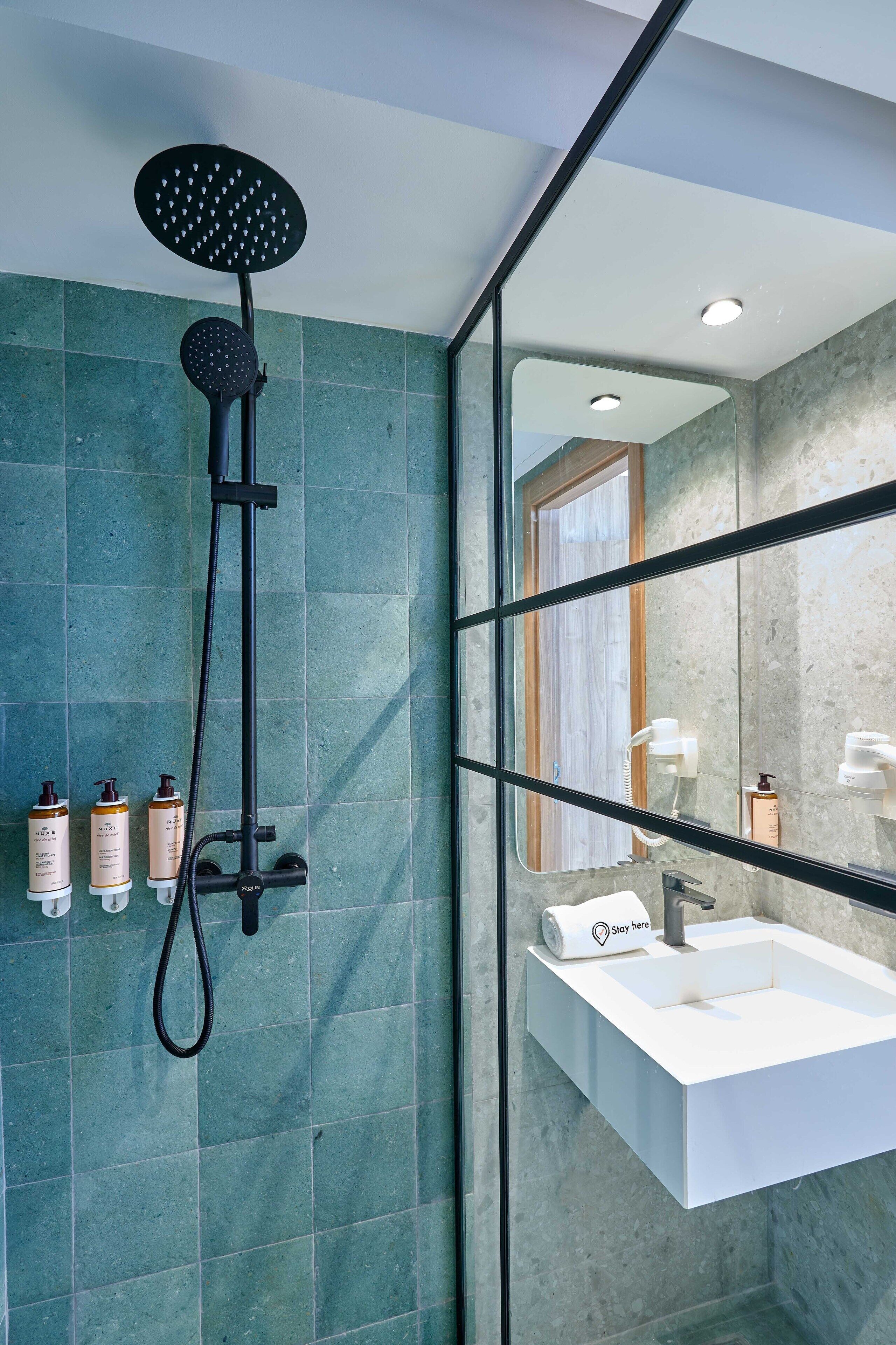 Een moderne badkamer met een douche, wastafel en toiletartikelen.