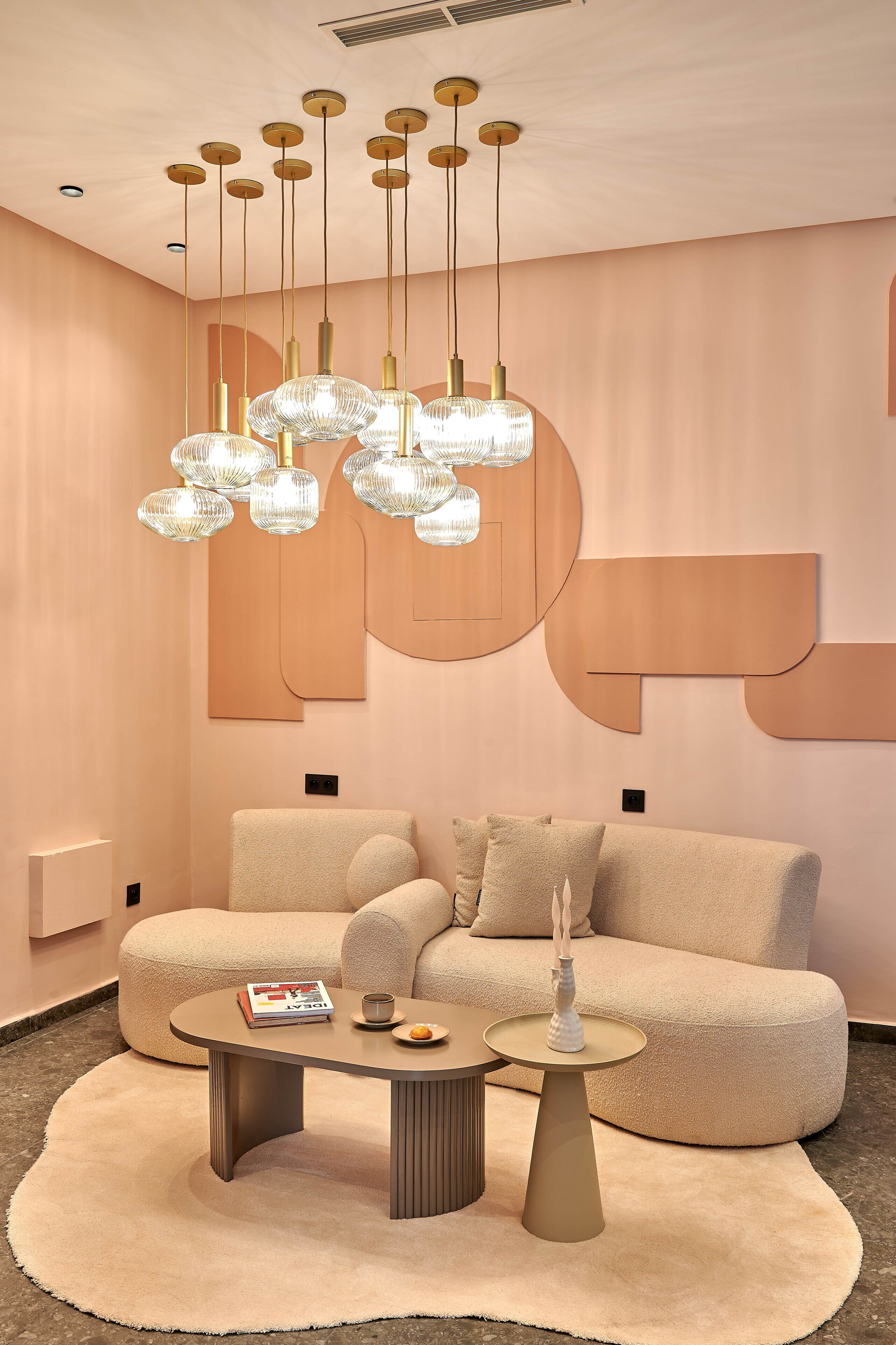 Una sala moderna con un sofá color beige, una mesa de centro y una lámpara de araña única.