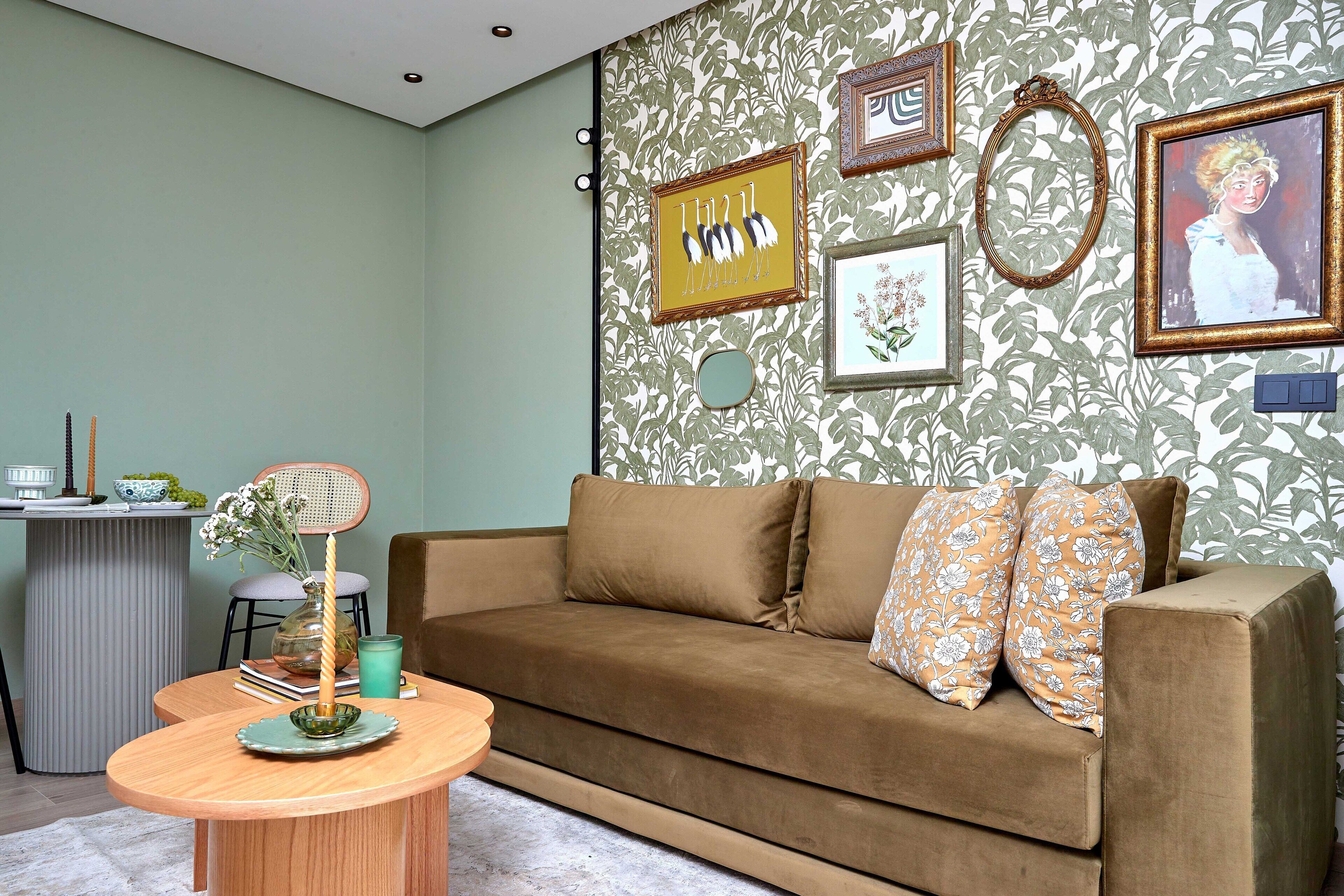 A living room with a brown sofa, a round wooden table, and a patterned wallpaper.