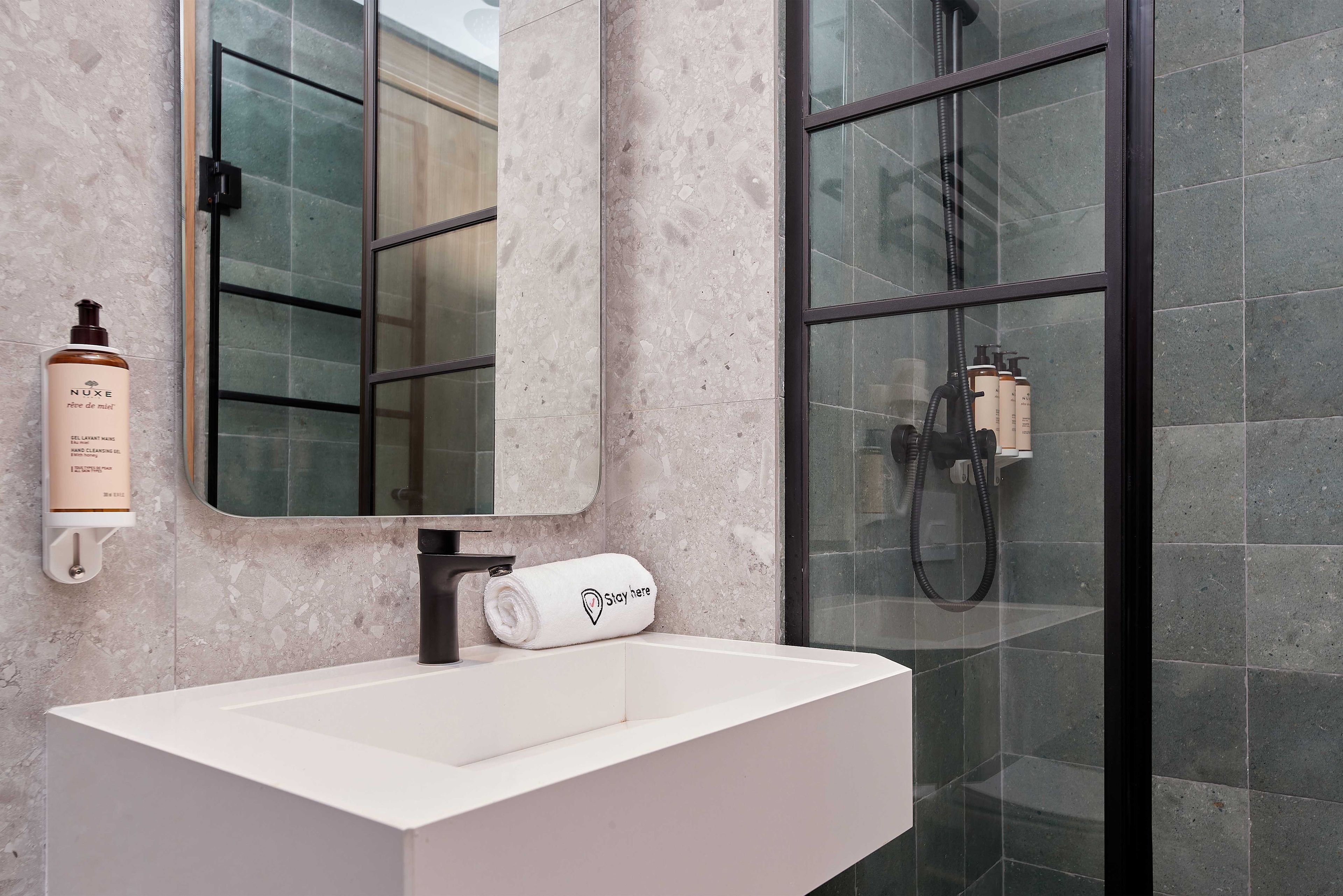 Een moderne badkamer met een witte wastafel, een spiegel en een douchecabine met glazen wanden.
