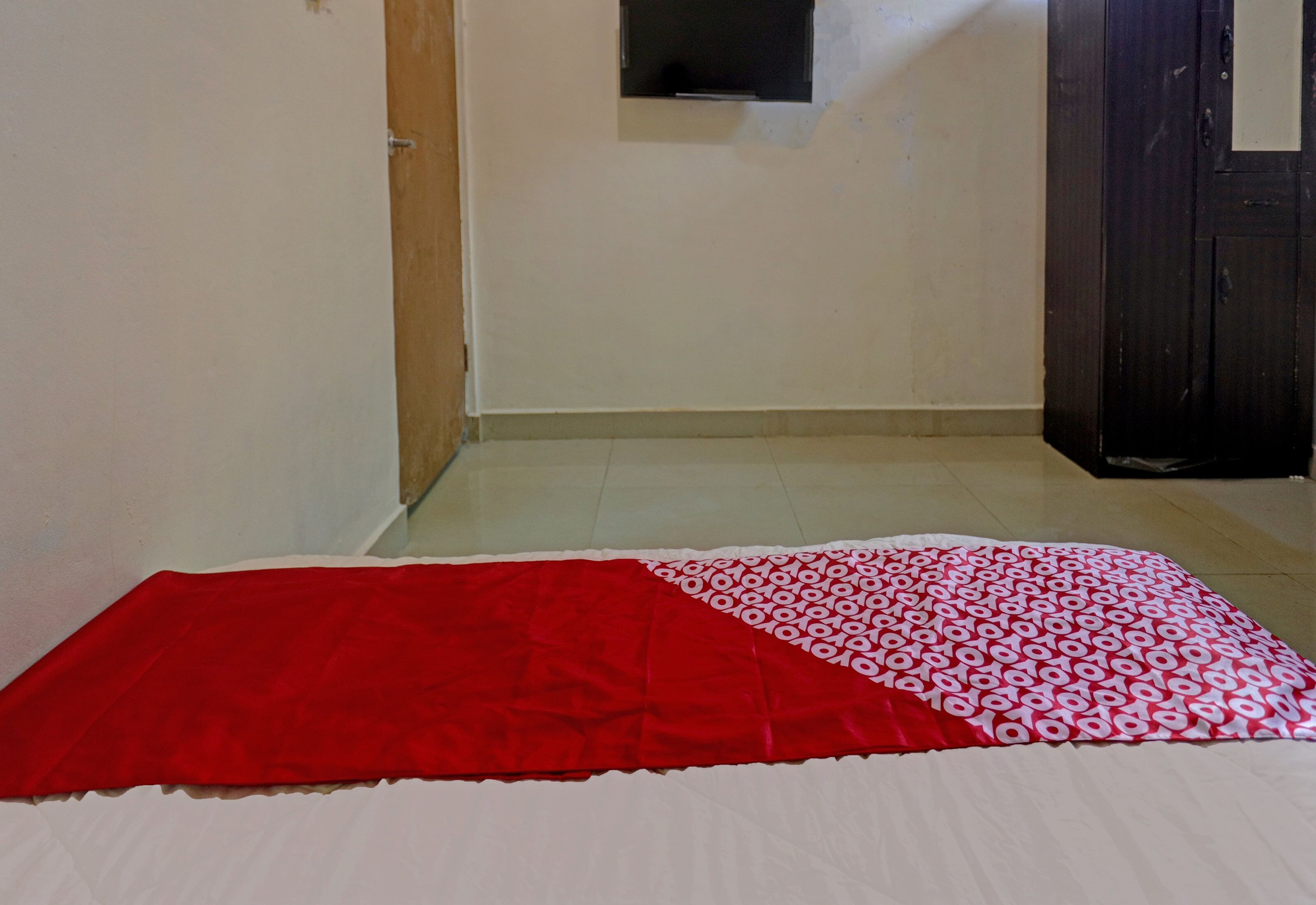 A room with a bed, a wooden door, and a window.