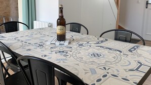 Ein Essbereich mit einem Tisch für vier Personen, einer Weinflasche und einer Treppe im Hintergrund.