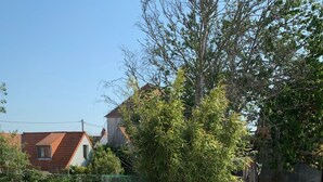 Eine hölzerne Terrasse im Freien mit einem runden Tisch und Stühlen, umgeben von einem Holzzaun.