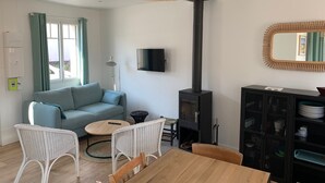 Ein modernes Wohnzimmer mit einer Couch, einem Esstisch, Stühlen, einem Fernseher, einem Kamin und einem Spiegel.