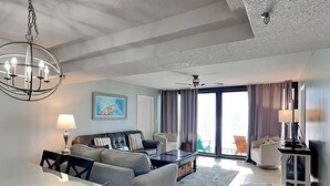 A modern living room with a sofa, a dining table, and a ceiling fan. - Watercrest #807 | Beach Views + Resort Pool! (Panama City Beach)