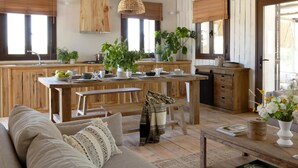 Eine gemütliche Küche mit Holdekor, einer zentralen Kochinsel mit Sitzgelegenheiten und einem Essbereich mit Sofa und Couchtisch.