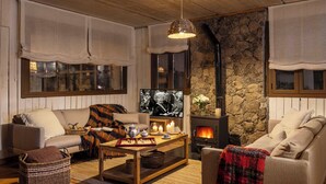 Ein gemütliches Wohnzimmer mit Kamin, Fernseher und bequemen Sitzgelegenheiten.