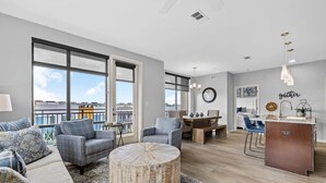 Una sala de estar moderna con un ventanal grande, una mesa de centro redonda de madera y un comedor con isla de cocina.