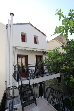 A two-story building with a balcony, a staircase, and a small outdoor area with a bicycle.