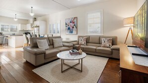 A modern living room with a sofa, coffee table, and a painting on the wall. - Sampson Cottage | Historic Charm (Orange)