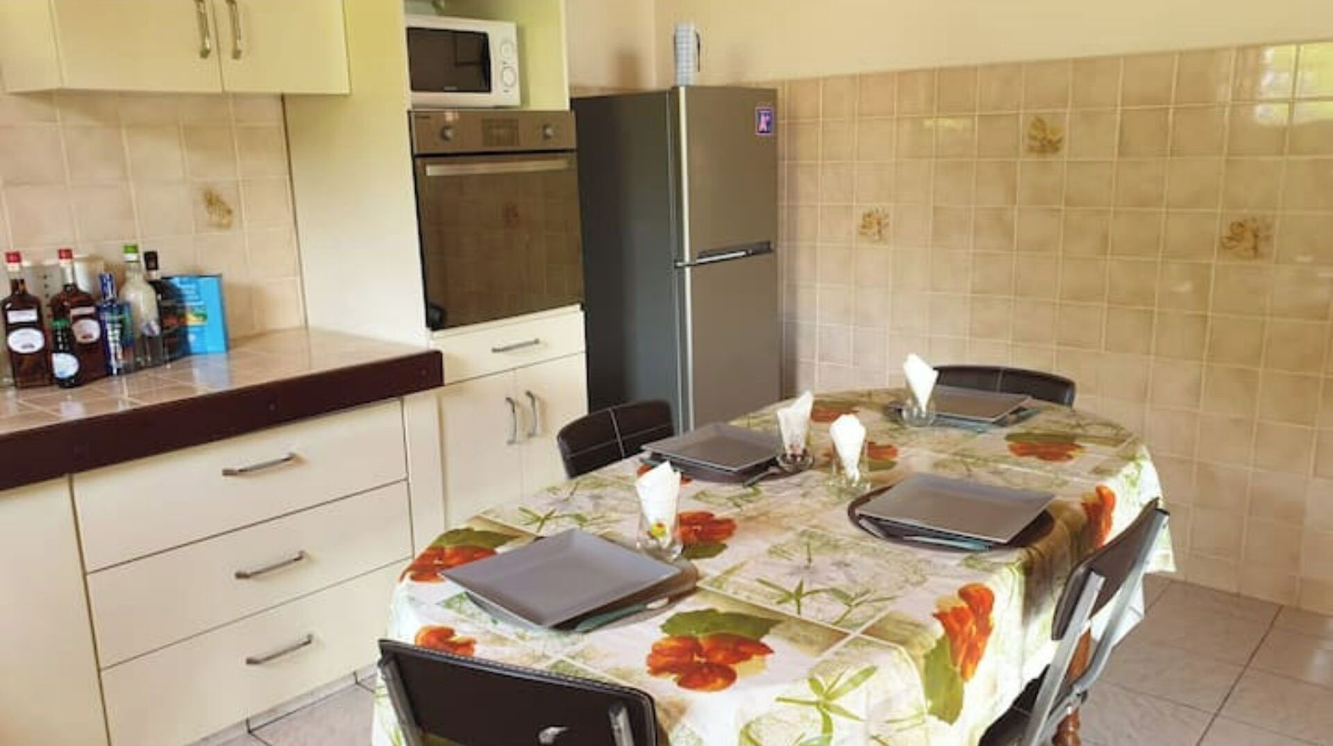 A kitchen with a dining table, cabinets, a refrigerator, and a microwave.