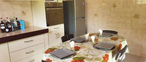 A kitchen with a dining table, cabinets, a refrigerator, and a microwave.