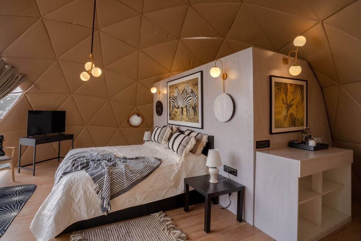 A bedroom with a bed, bedside tables, a desk, and wall art.