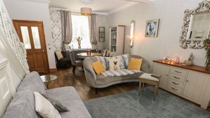 Un salon chaleureux avec un canapé gris, une petite table ronde et un meuble.