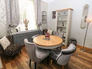 A dining area with a round wooden table, grey upholstered chairs, a zebra-patterned sofa, a radiator, a bookshelf, and a floor lamp. - 5 Pontardulais Road (Llanelli)