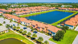 Zona residencial con varias casas de dos pisos, un estanque grande en el centro y un césped bien cuidado.