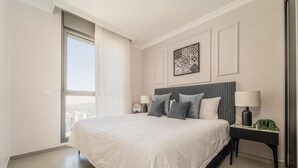 A bedroom with a large bed, two bedside tables with lamps, a patterned headboard, and a city view through a window. - Dreamy  2BDR, Unparalleled Views Of The Old City (Jerusalem)