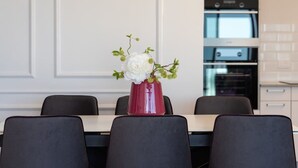 A dining area with a table set for four, a red vase with white flowers, and a modern kitchen in the background. - Dreamy  2BDR, Unparalleled Views Of The Old City (Jerusalem)