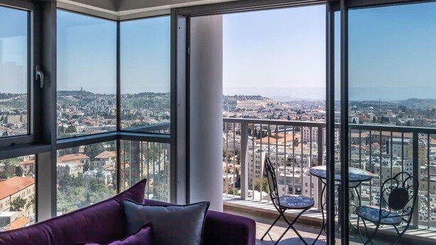 A balcony with a city view, a purple sofa, and two small tables. - Dreamy  2BDR, Unparalleled Views Of The Old City (Jerusalem)