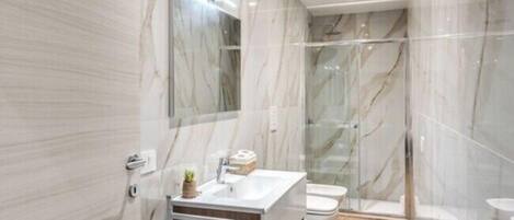 Une salle de bain moderne avec des murs en marbre, une douche en verre et un meuble-lavabo en bois.
