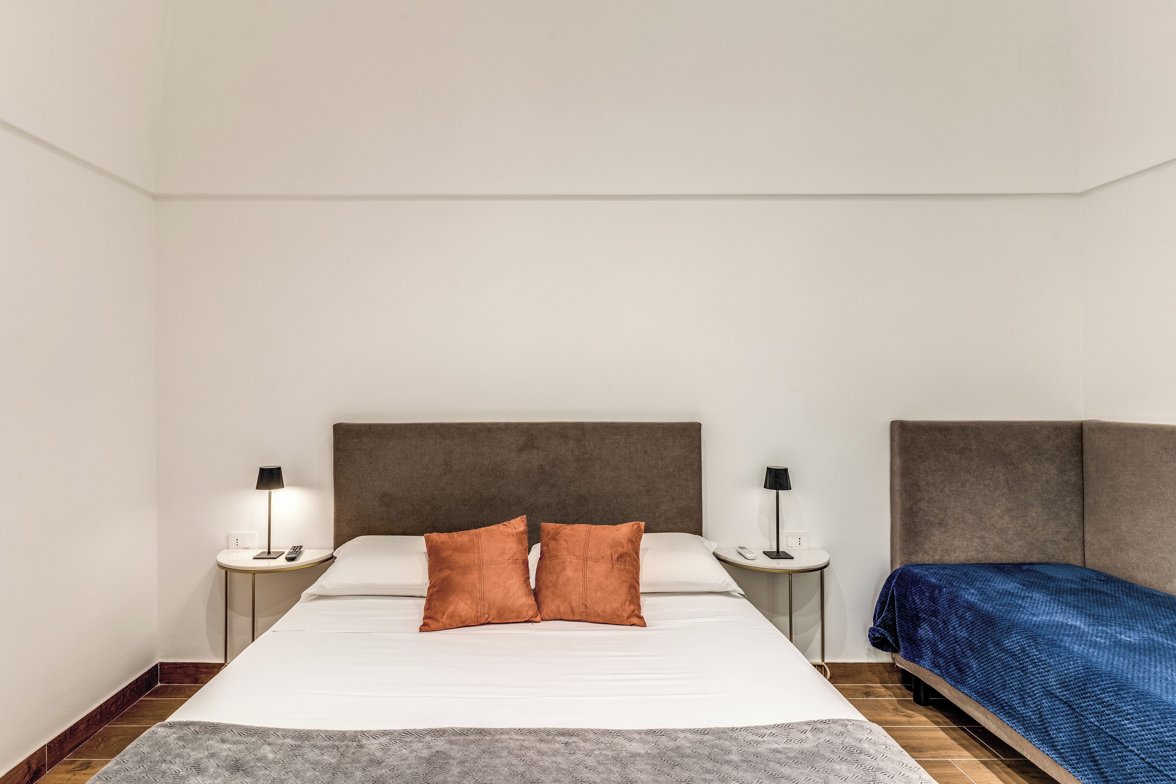 A hotel room with a large bed, two bedside tables, a nightstand, and a blue blanket.