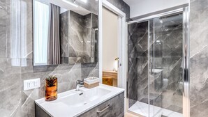 A modern bathroom with a marble sink, a large mirror, and a glass shower enclosure. - Domus Partenopea  (Naples)