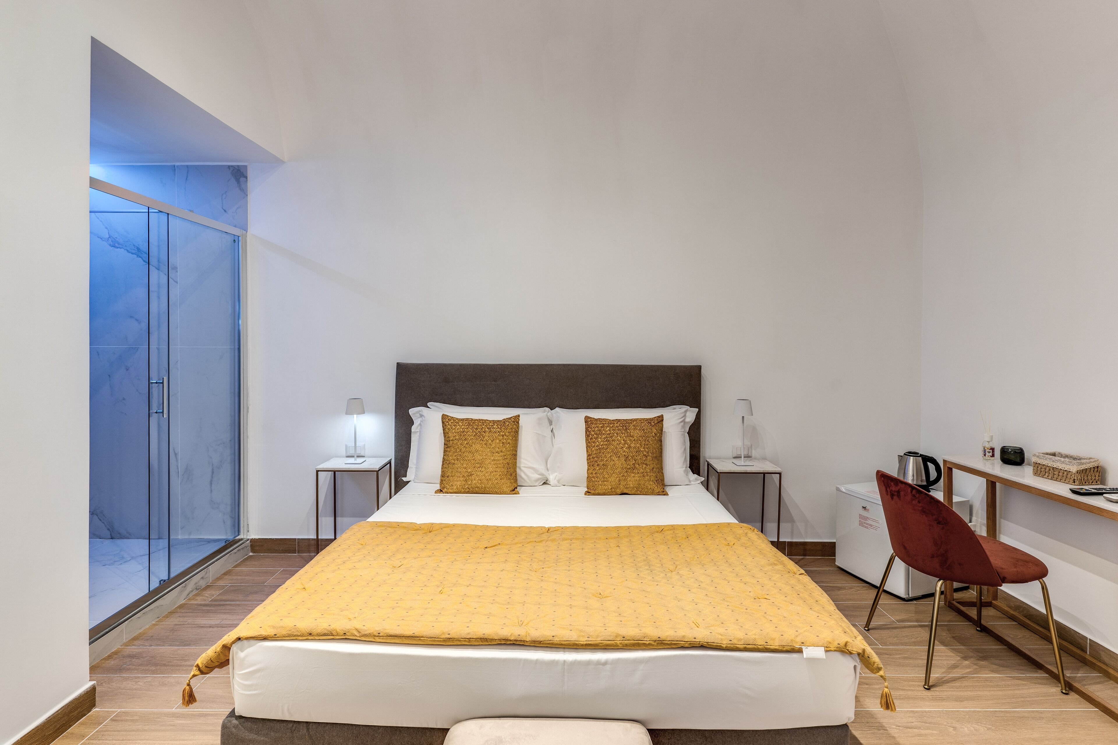 Een moderne hotelkamer met een groot bed, een bureau, een stoel en een kleine kitchenette.