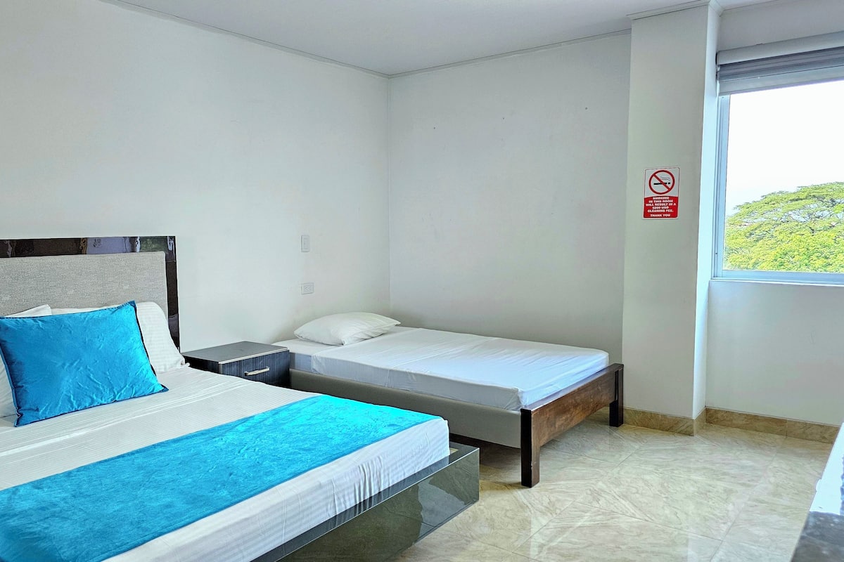 Een hotelkamer met twee bedden, een nachtkastje, een raam en een rookvrij bord.