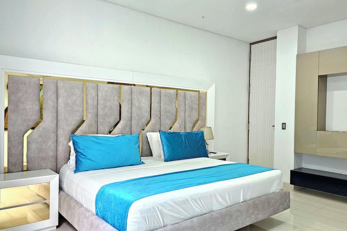 Een moderne slaapkamer met een groot bed, een aan de muur bevestigde televisie en een nachtkastje.