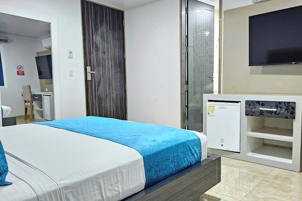 Een hotelkamer met een bed, een bureau met een televisie, een stoel en een kledingkast.