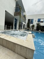 Una piscina al aire libre, sombrillas, sillones reclinables de piscina