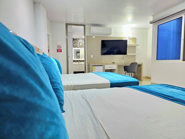 Habitación de hotel con dos camas, un escritorio, una silla, un televisor y una ventana.