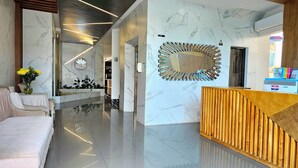 A hotel lobby with a marble floor, a reception desk, a sofa, and a decorative mirror. - Lotto Hotel Boutique (Cali)