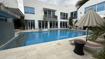 Een buitenzwembad, parasols voor strand/zwembad