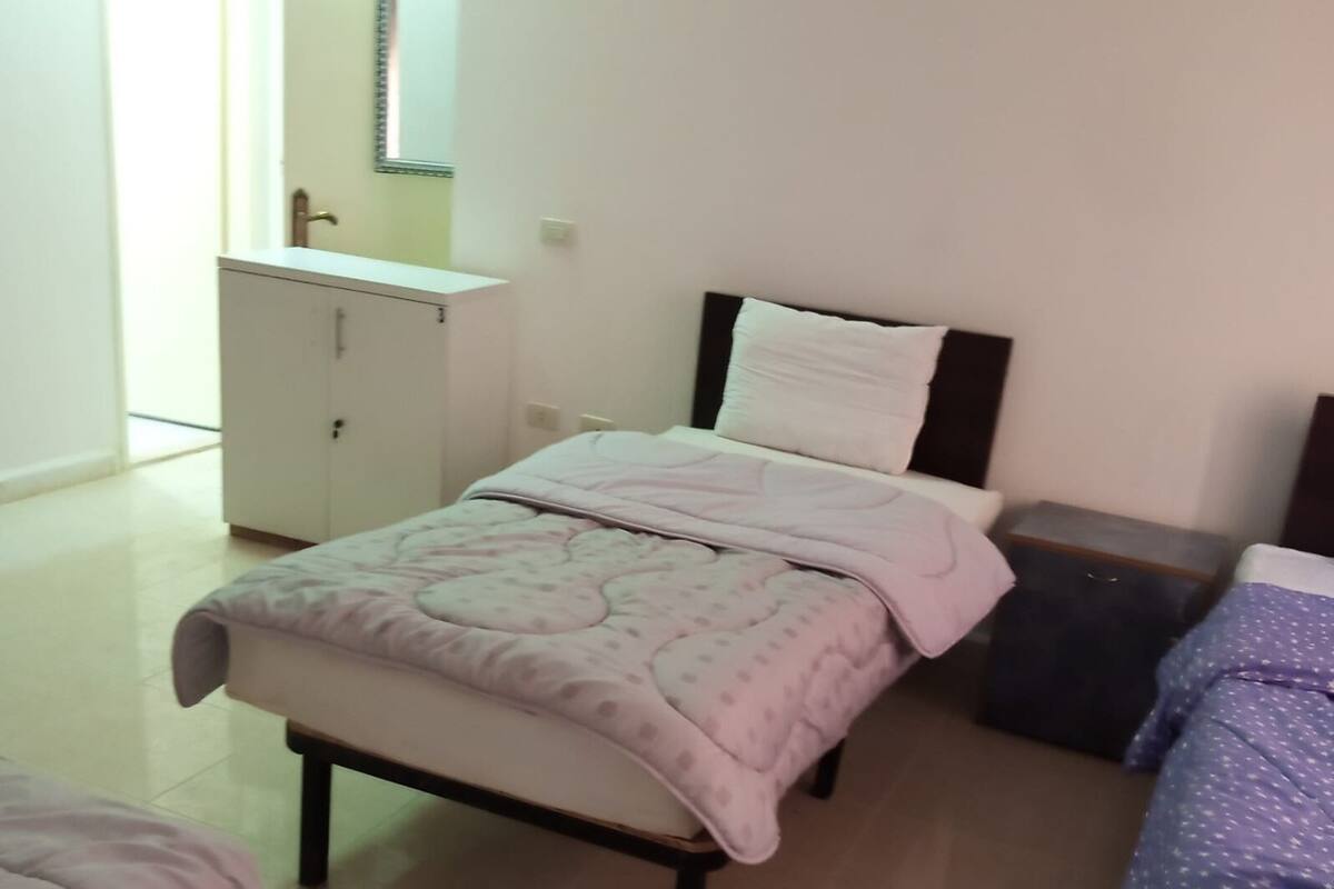 A bedroom with a bed, a bedside table, a dresser, and a window.