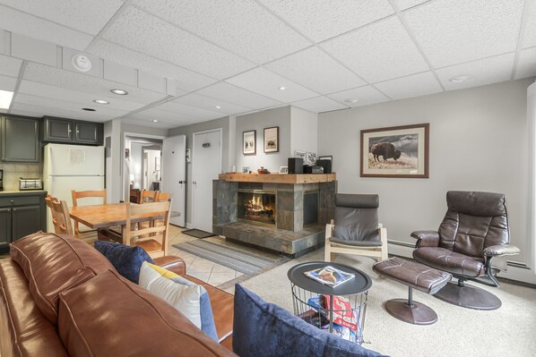 A modern living room with a fireplace, leather furniture, and a dining area.