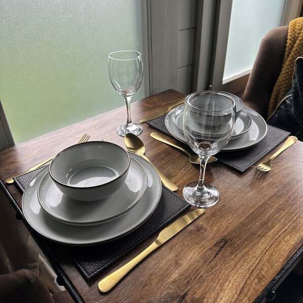 A dining table set with plates, bowls, cutlery, and wine glasses.