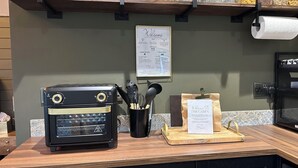 Una encimera de cocina con una cafetera, utensilios y un cartel de bienvenida.