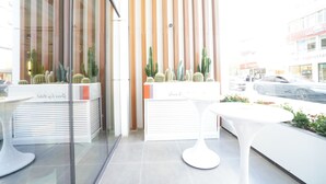 A modern indoor space with glass partitions, white furniture, and cacti. - IBOS HOTELS IZMIR (Izmir)