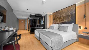 A modern hotel room with a large bed, a desk, and a dining area.